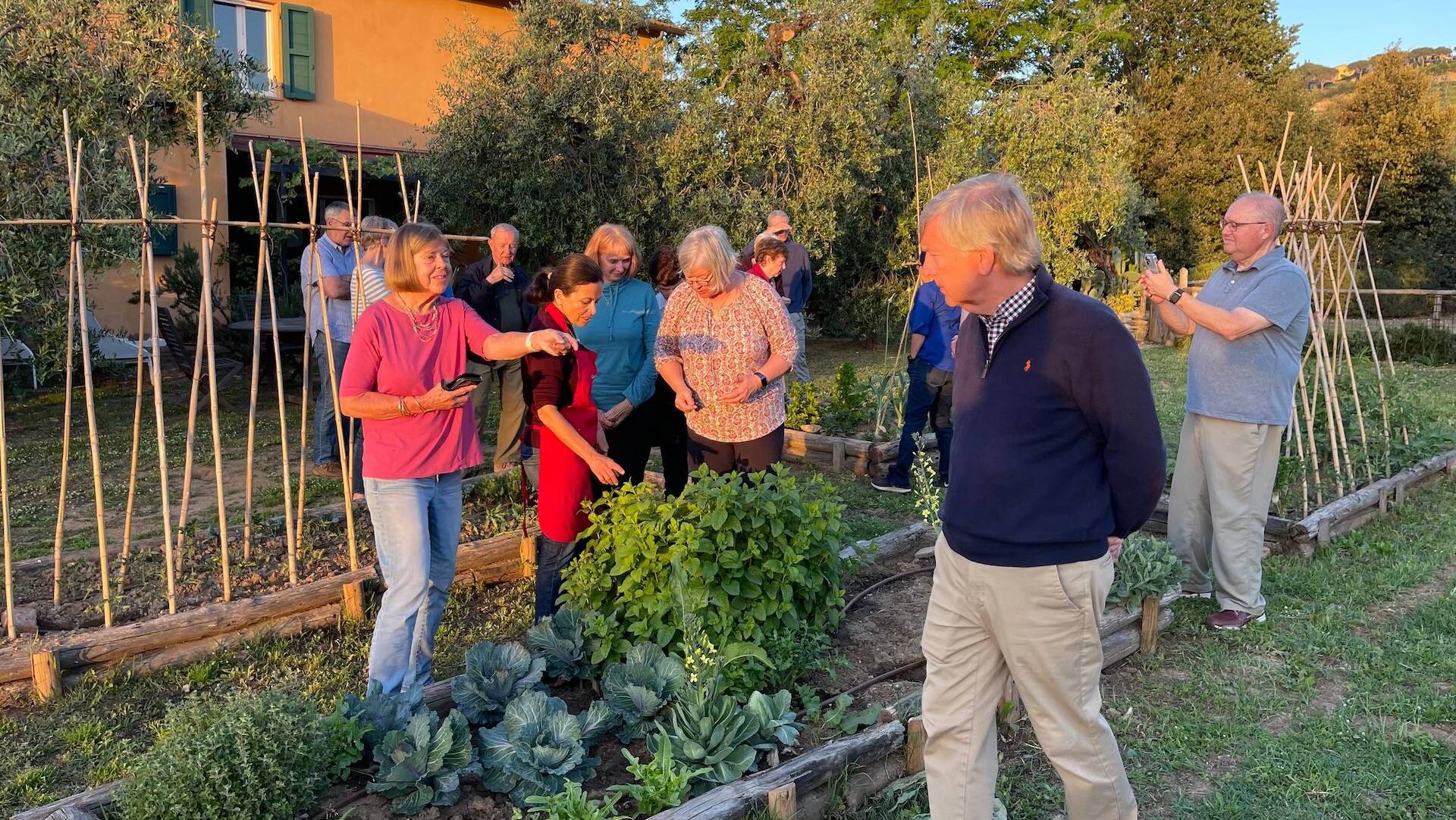 Guests gather with Chicca in the vegetable garden at her Tuscan farmhouse during a Cooking in Tuscany class.